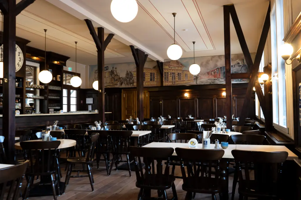Gesamtansicht des Wirtshaus-Innenraums mit Tresen, Tischen und Sitzbereichen.