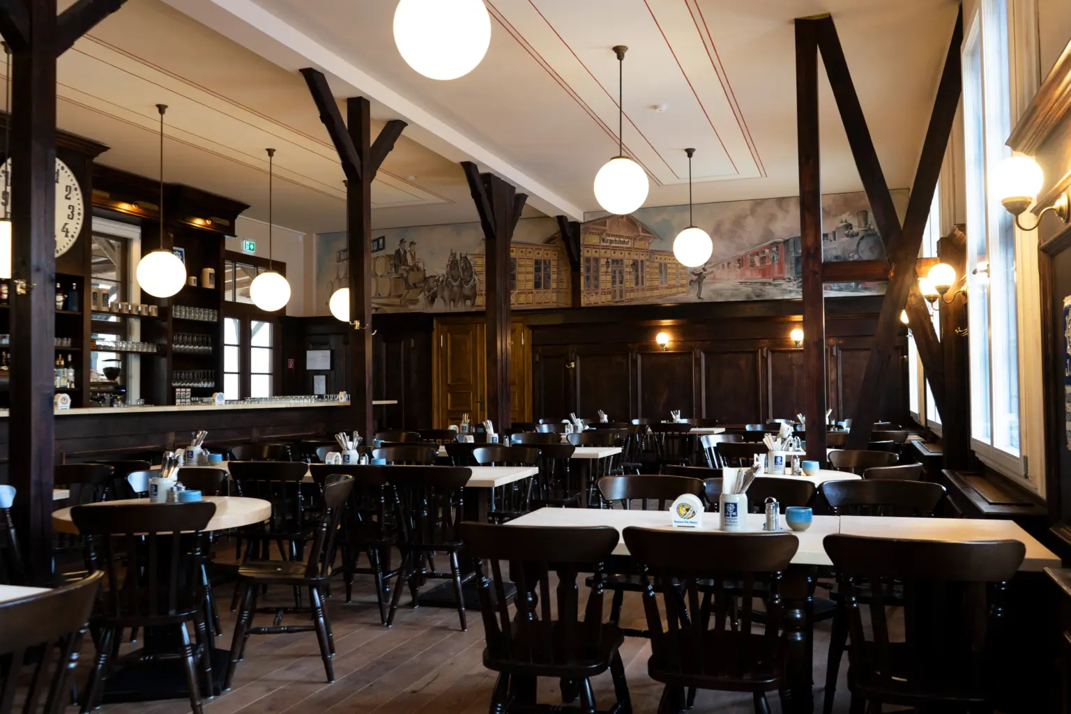 Gesamtansicht des Wirtshaus-Innenraums mit Tresen, Tischen und Sitzbereichen.