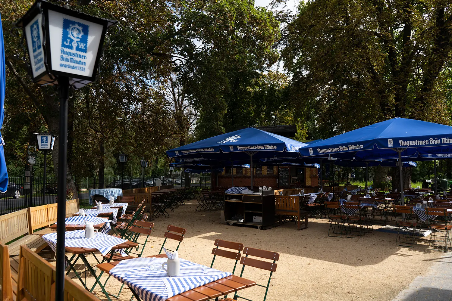 Außenbereich des Augustiner am Bürgerbahnhof mit Biergarten und Sitzplätzen im Grünen.
